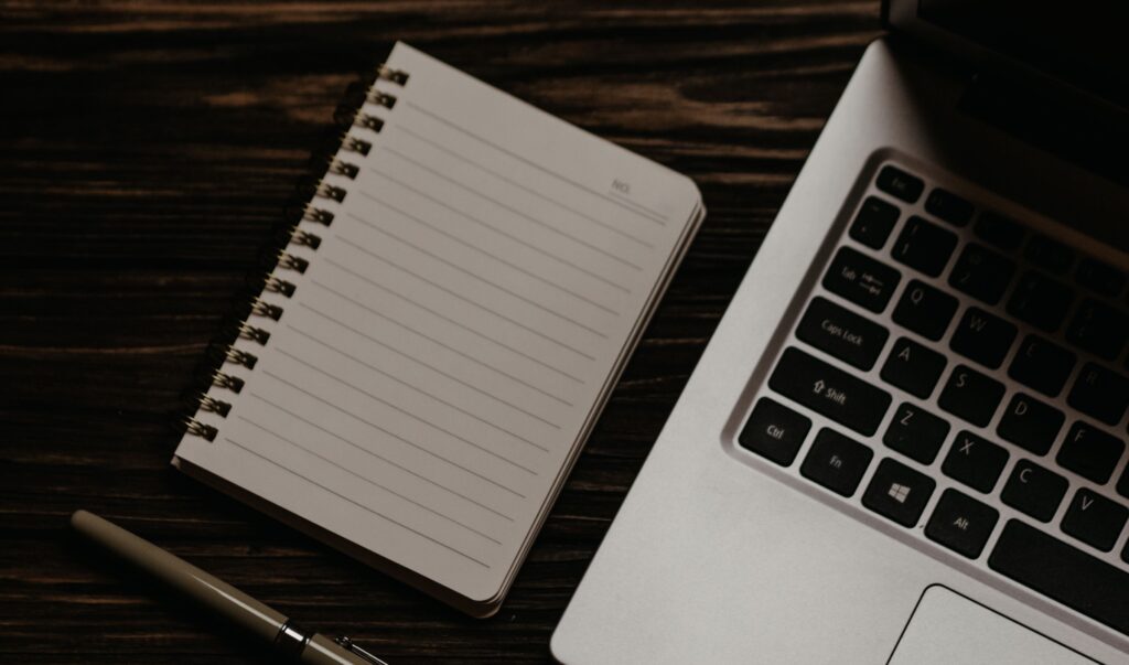 digital marketing expert writing content in a notepad with a laptop